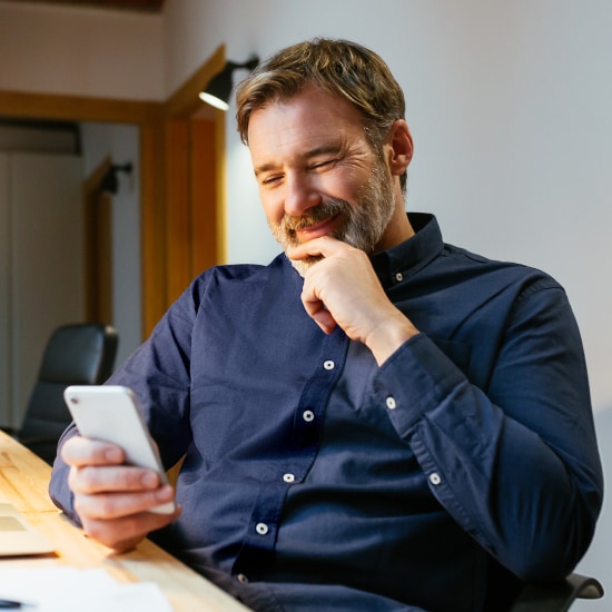 Ein Kunde der Consorsbank schaut auf sein Handy