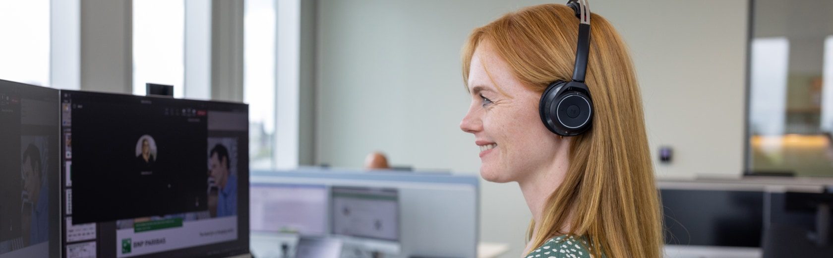 An employee with earphones sits at a computer